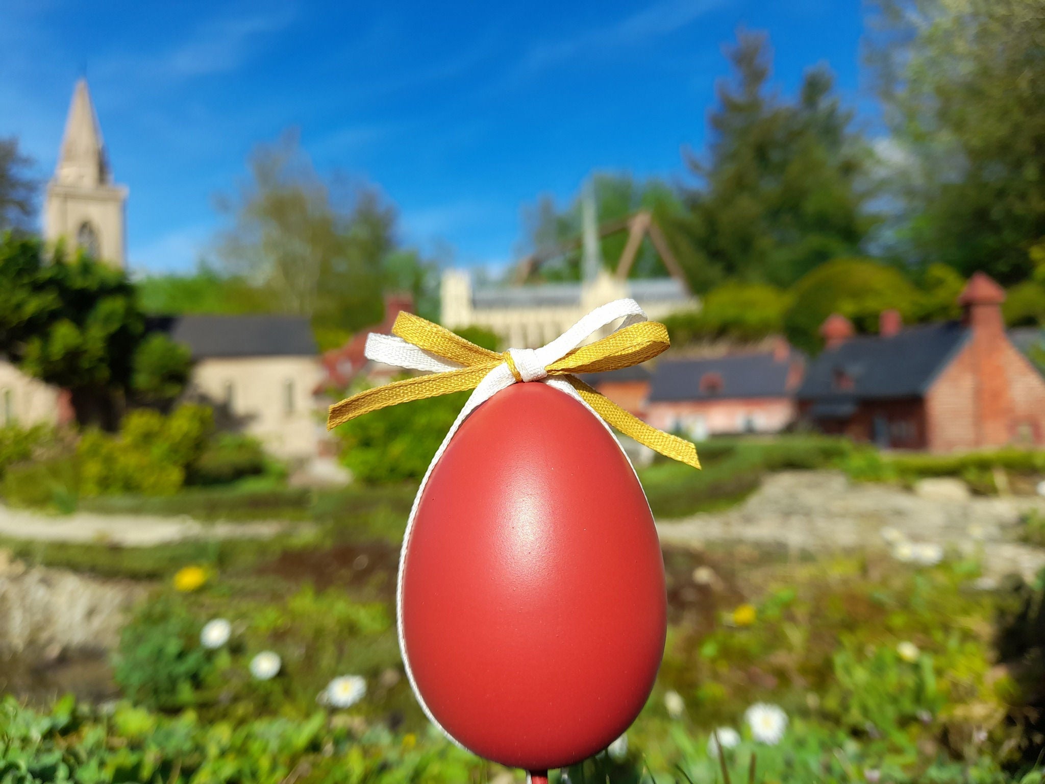A red Easter egg with a ribbon sits among miniature monuments.