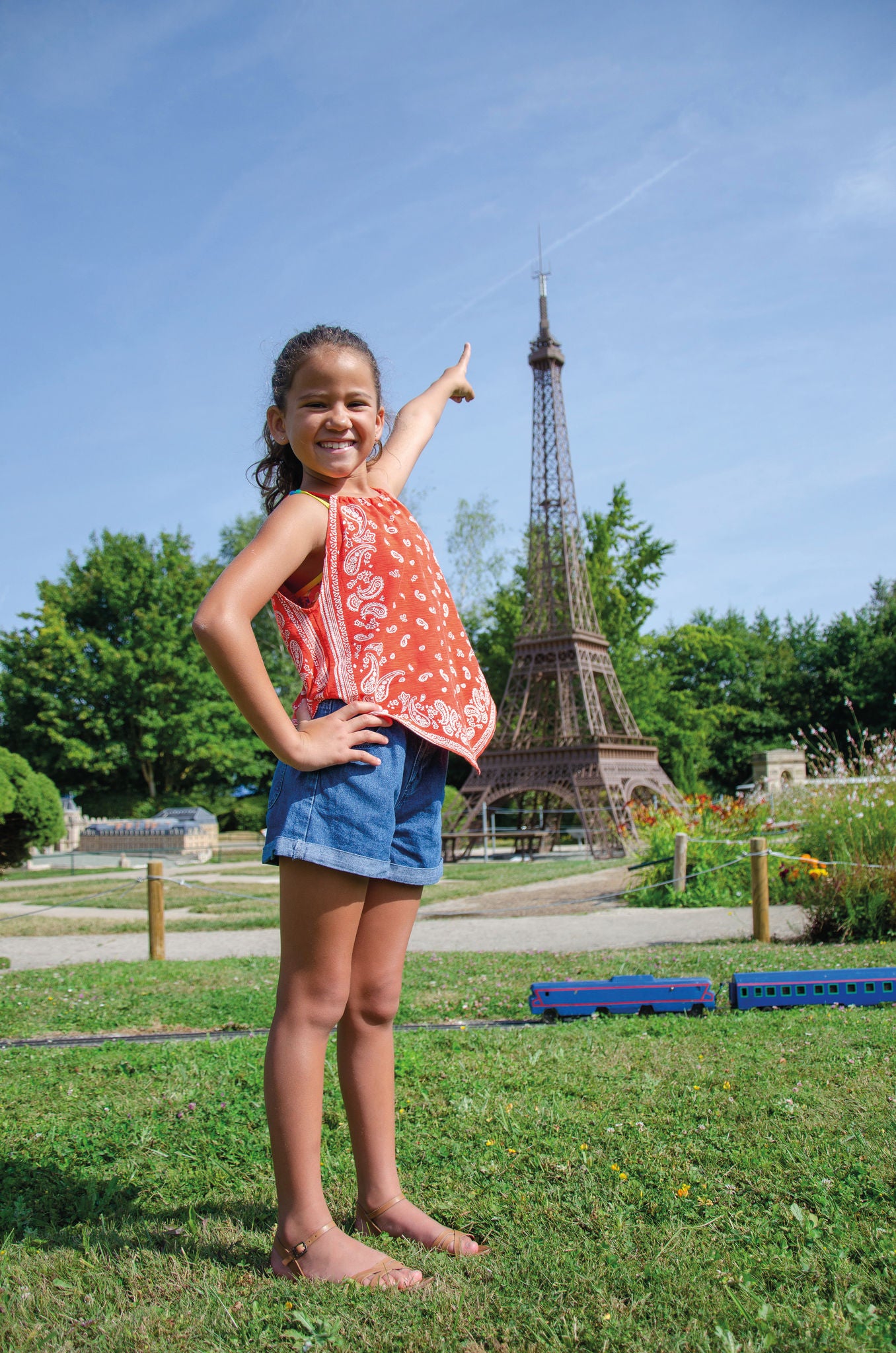 Picture of a girl pointing her finger at Eiffel tower miniature at France Miniature 